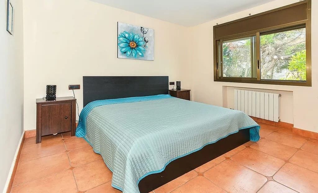 Спальня с большой кроватью и окнами на сад.