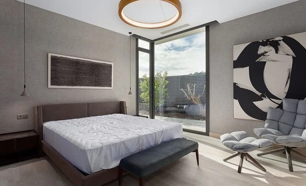 Главная спальня с большими окнами и дизайнерской мебелью