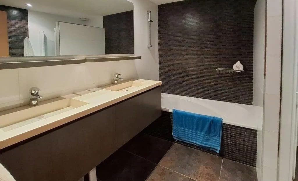 Ванная комната с ванной, душевой и двойной раковиной.