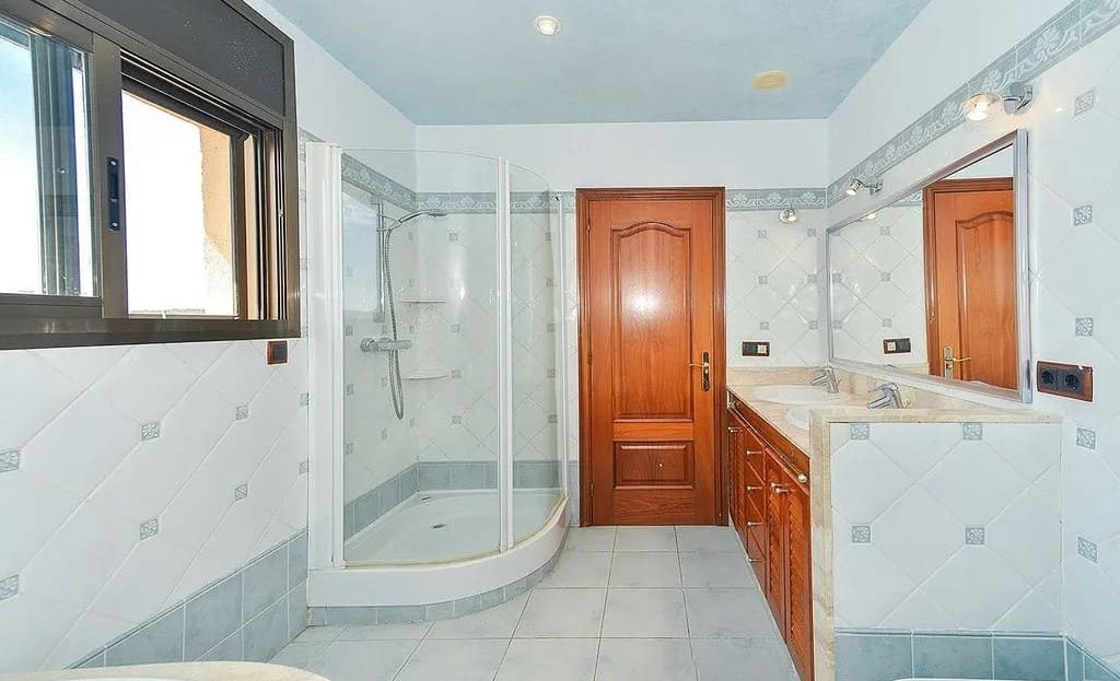 Ванная комната с душевой кабиной и двойной раковиной.