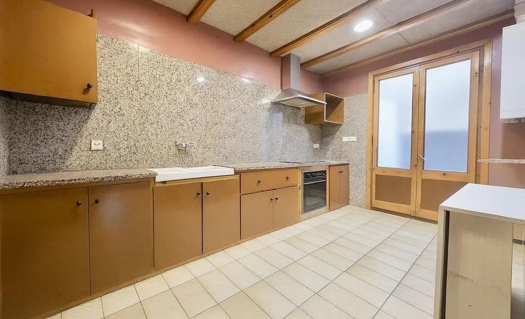 Просторная кухня с длинной рабочей поверхностью и выходом к окну.