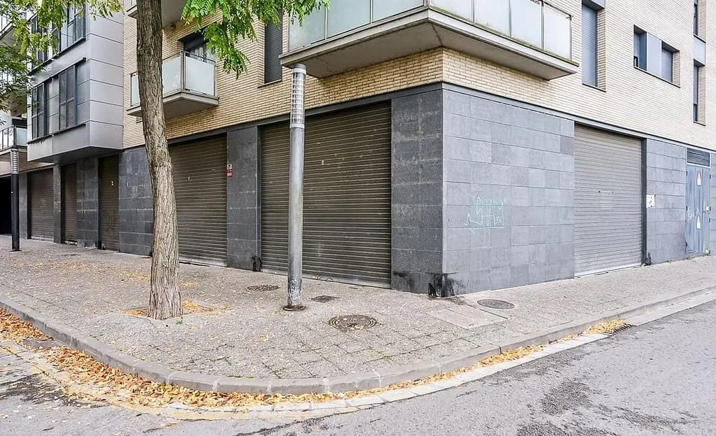 Угловой вид на фасад здания с витринами коммерческих помещений и тротуаром