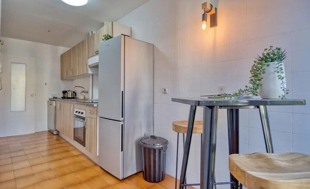 Кухня с барной стойкой, холодильником и декоративным освещением.