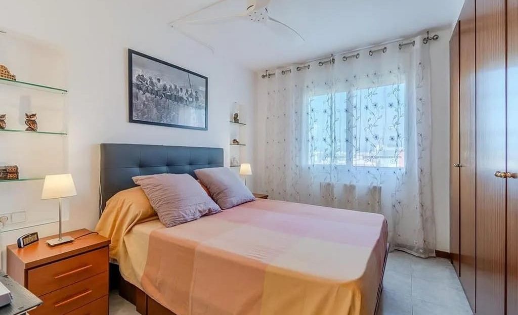 Спальня с двуспальной кроватью и большим окном.