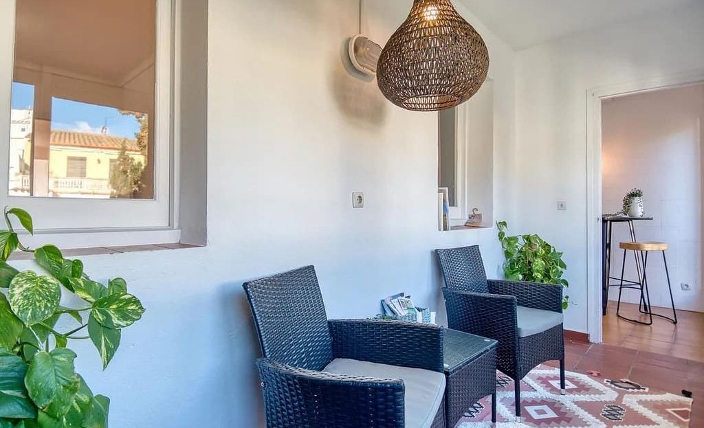 Просторная терраса с плетёными креслами и подвесным светильником.