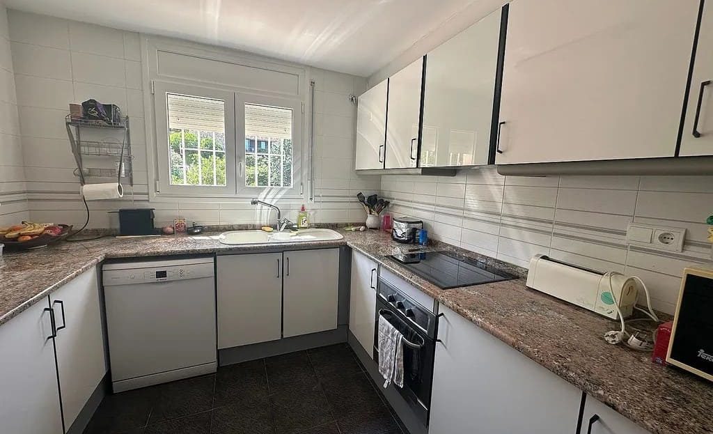 Кухня с окном, белыми шкафами и рабочей поверхностью.