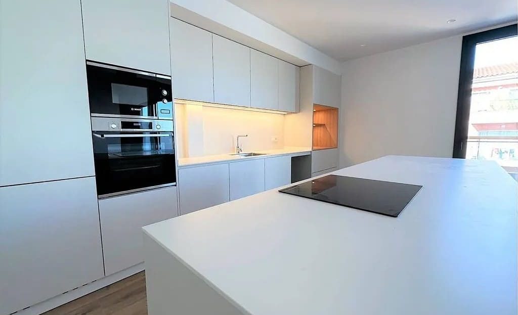 Минималистичная белая кухня с встроенными духовым шкафом и гарнитуром