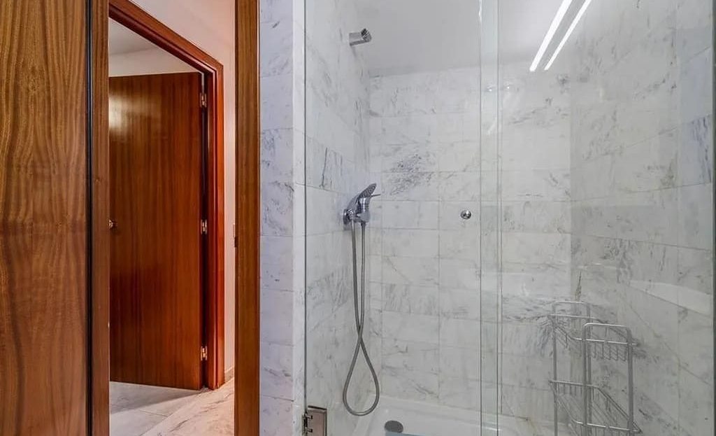 Ванная комната с душевой кабиной и мраморной отделкой
