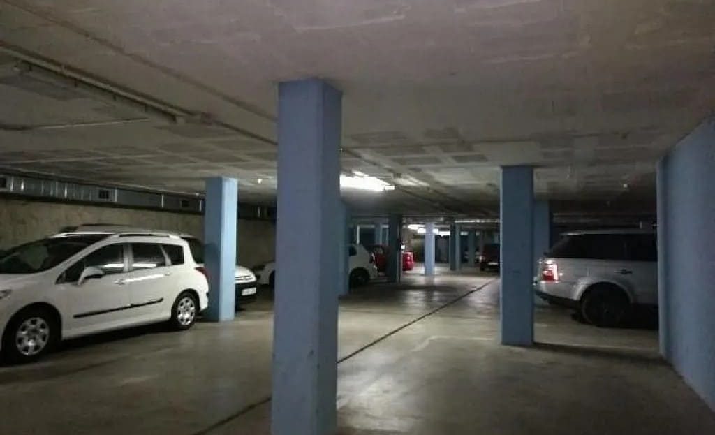 Подземный паркинг с колоннами и припаркованными автомобилями