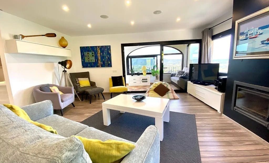 Современная гостиная с большими окнами и камином.