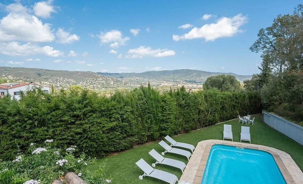 Вид на бассейн и сад с лежаками.