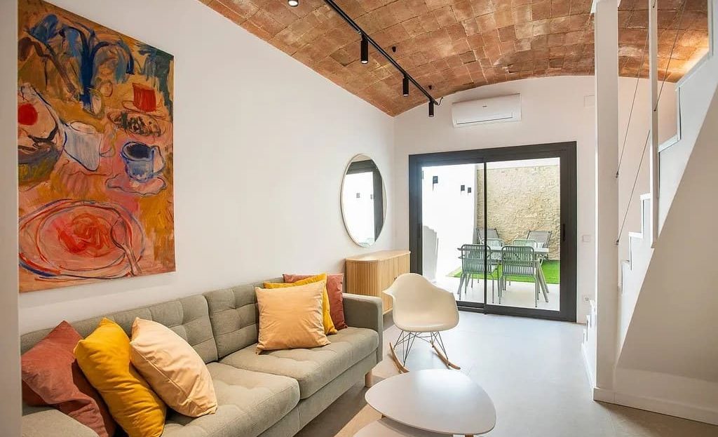 Гостиная с каменной стеной, диваном и выходом во внутренний двор