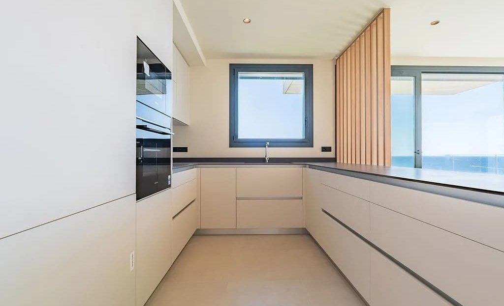 Светлая кухня открытой планировки с панорамными окнами и морскими видами