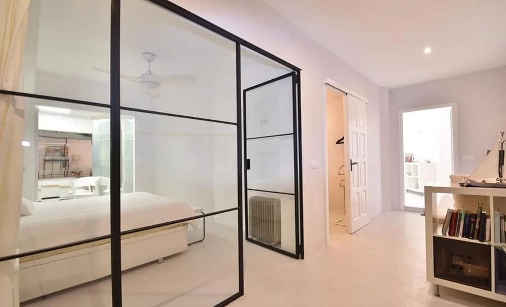 Спальня со стеклянной перегородкой и современной отделкой.