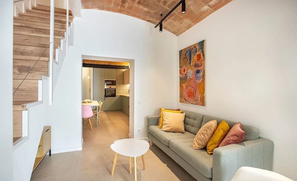 Гостиная с лестницей на второй этаж и оригинальным сводчатым потолком.