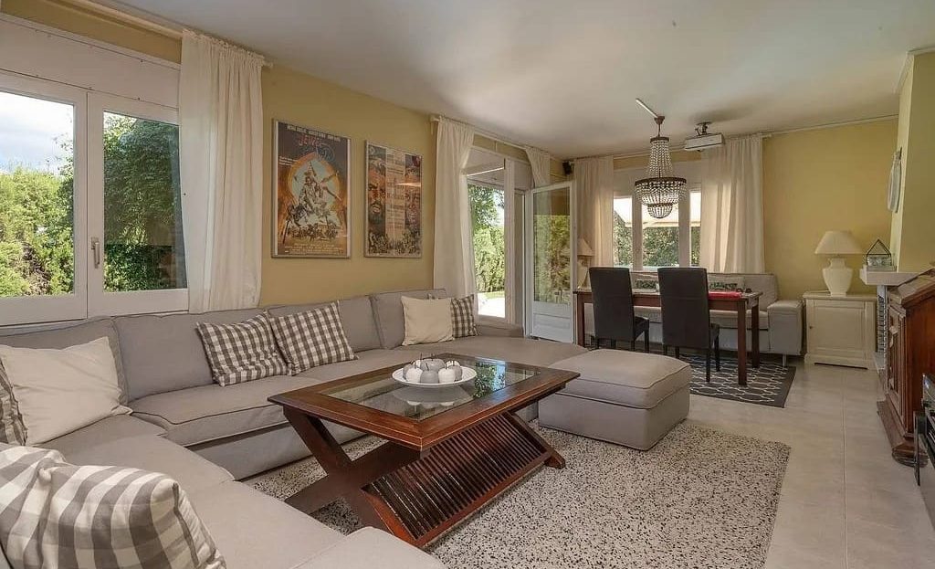 Просторная гостиная с большими окнами и мягкой мебелью.