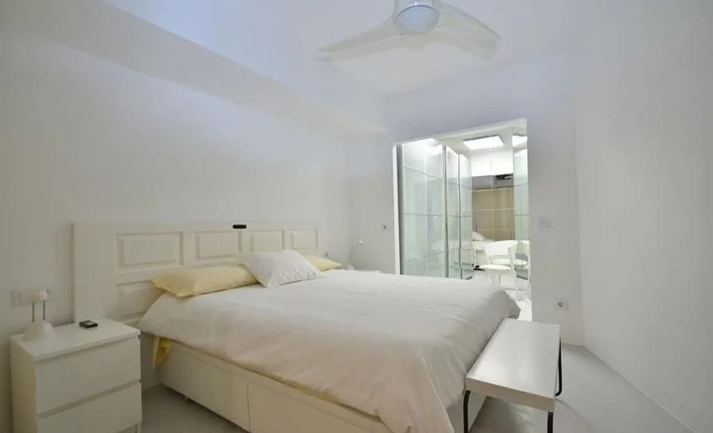 Главная спальня с большой кроватью и белым интерьером.