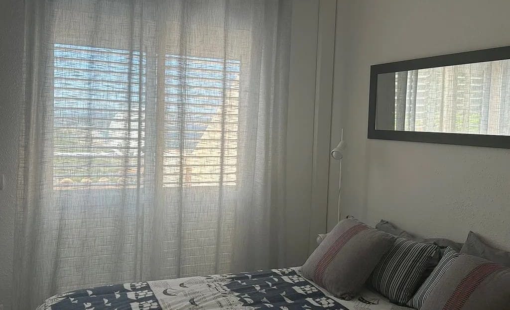 Спальня с двойной кроватью и окном с занавесками.