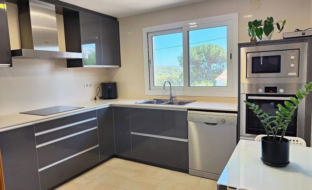 Современная кухня с окном и встроенной техникой.