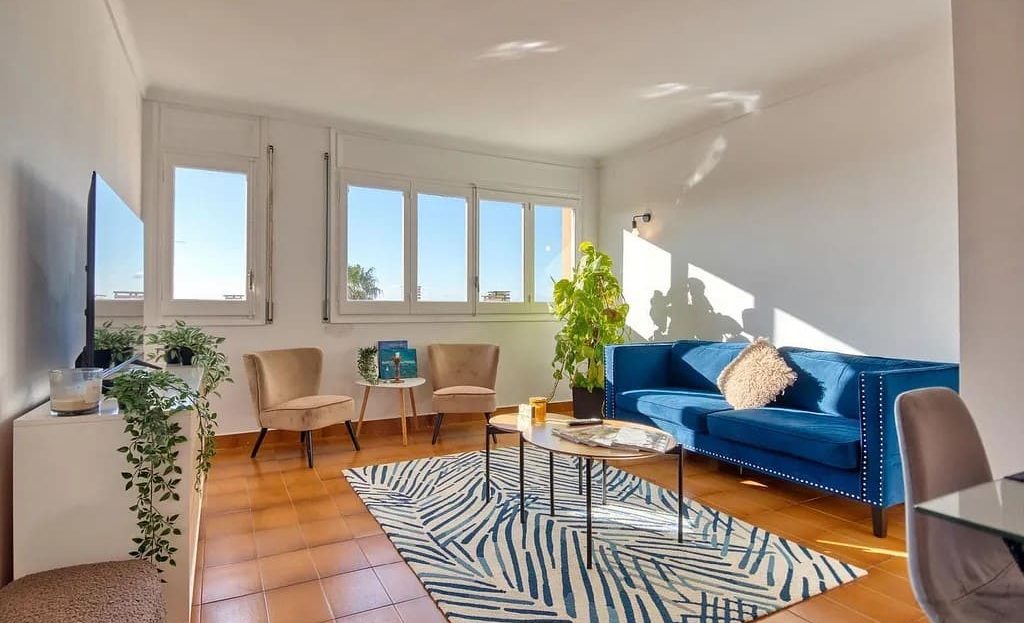 Гостиная с большими окнами, диваном и зоной отдыха.