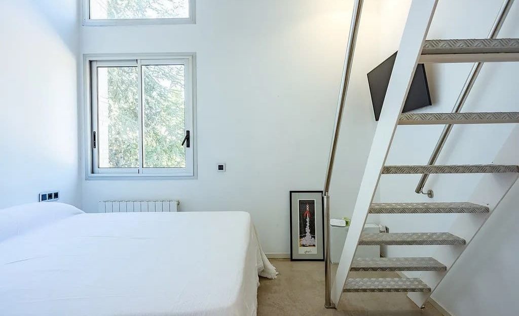 Спальня с высокими потолками и лестницей на антресоль