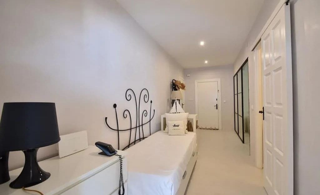 Длинный светлый коридор с мебелью и встроенными шкафами.