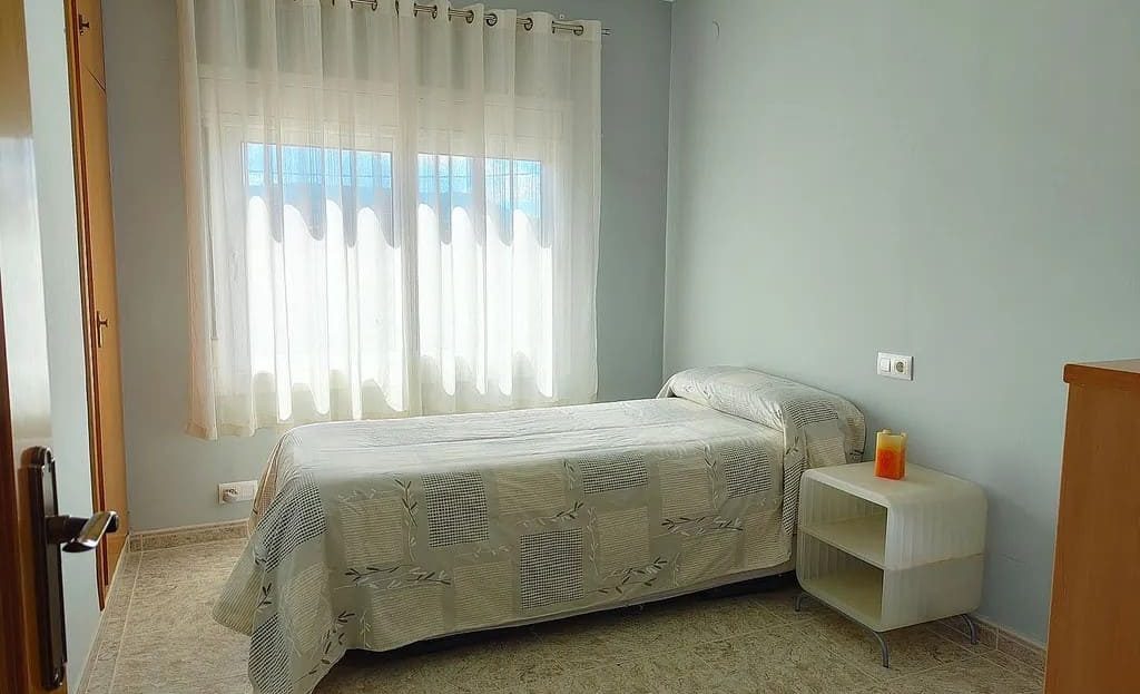 Спальня с односпальной кроватью и большим окном.