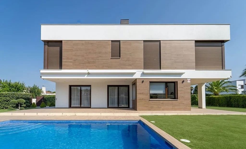Фасад современной виллы с бассейном и садом