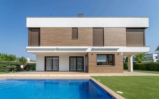 Фасад современной виллы с бассейном и садом