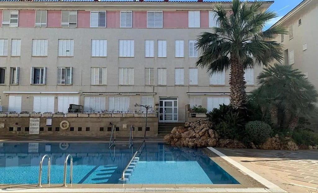 Общий вид жилого комплекса с бассейном перед фасадом здания.