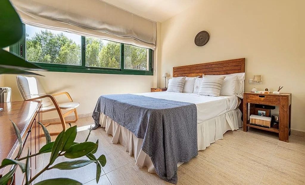 Спальня с двуспальной кроватью и видом на зелёную зону