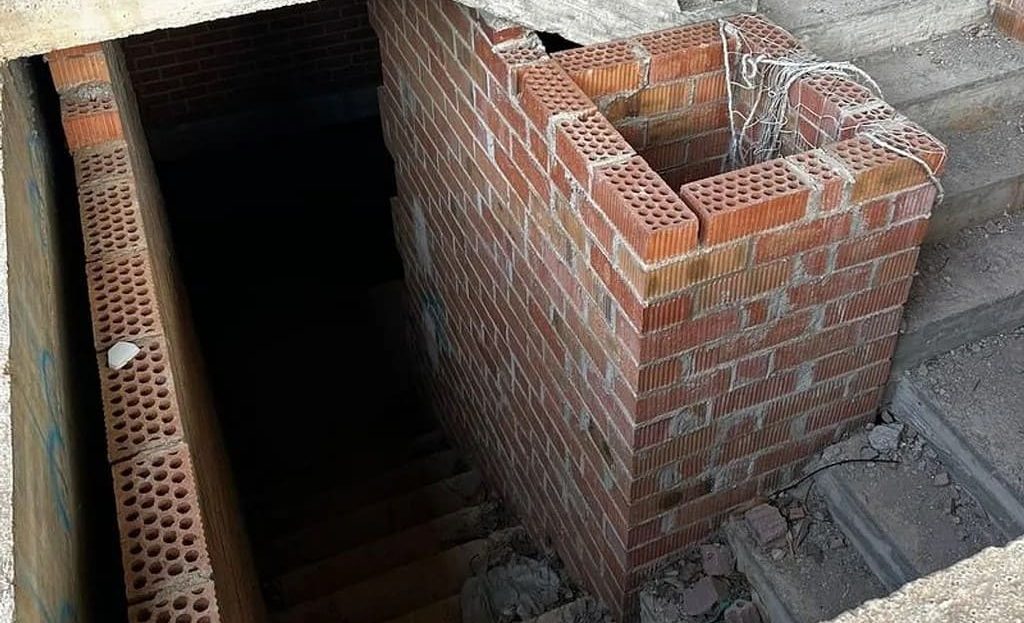 Нестроенная лестничная шахта с кирпичной кладкой и спуском вниз.