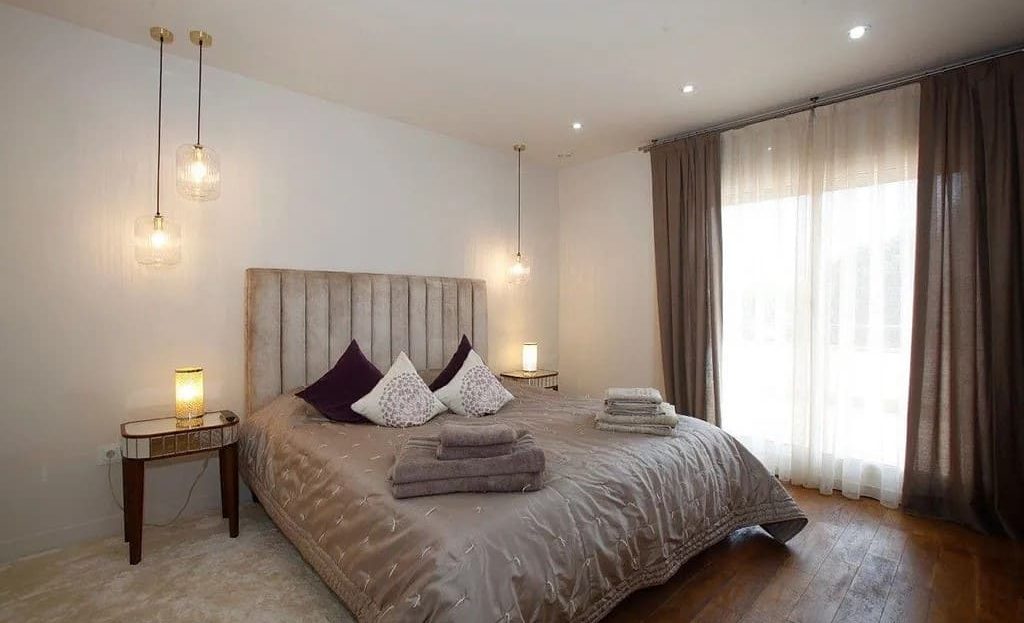 Спальня с двуспальной кроватью и панорамным окном.