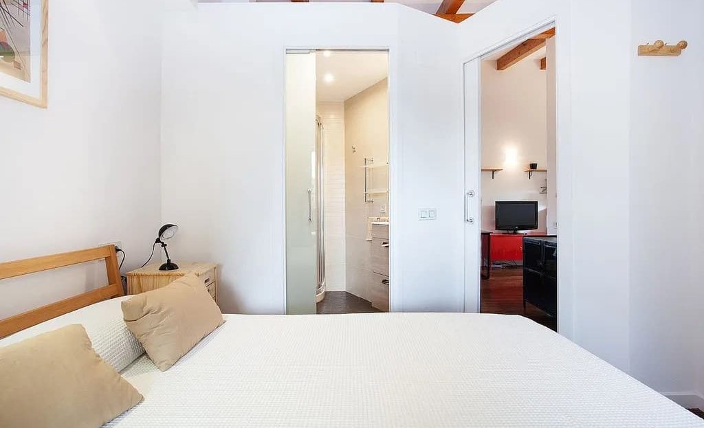 Спальня с видом на ванную комнату и деревянными балками