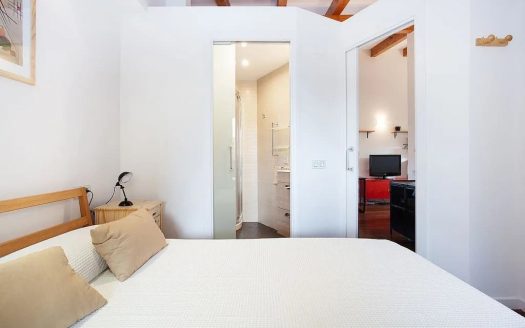 Спальня с видом на ванную комнату и деревянными балками