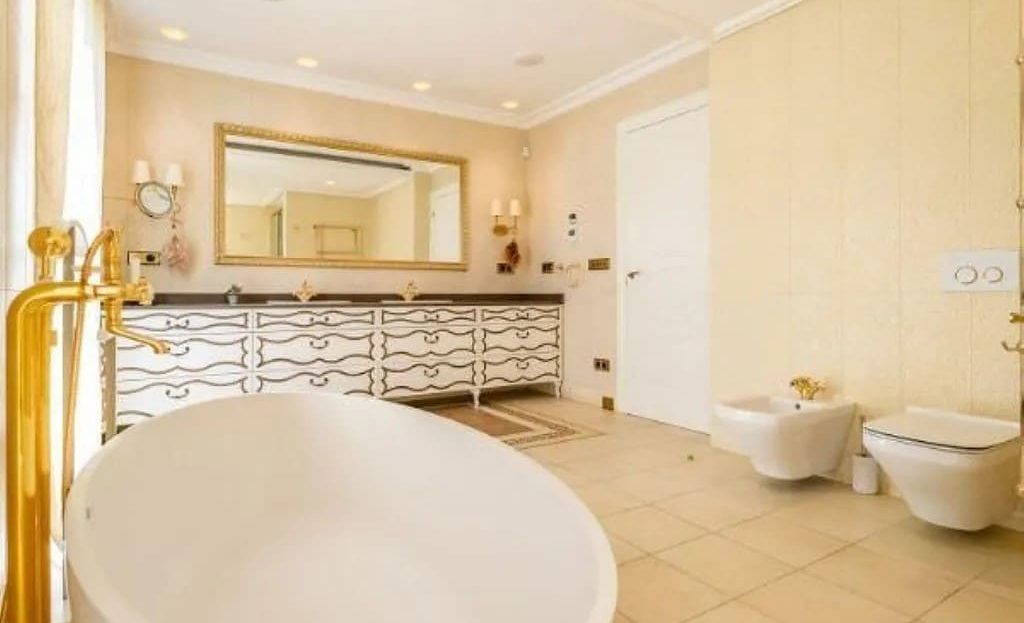 Роскошная ванная комната с золотыми деталями и отдельной ванной