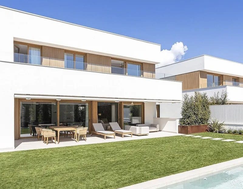 Фасад современной виллы с газоном и зоной отдыха у бассейна