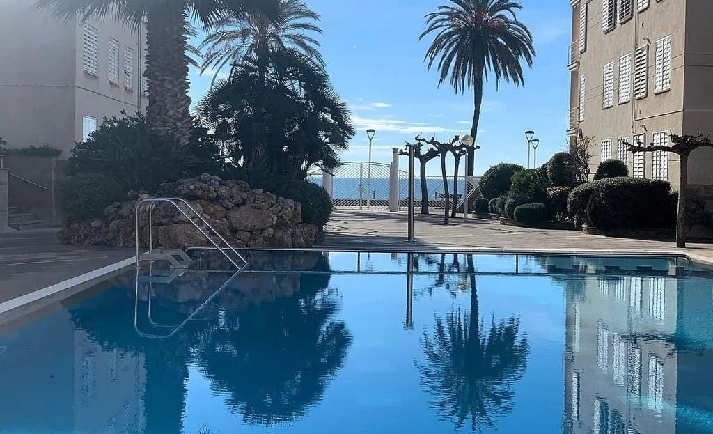 Бассейн с пальмами и видом на море между корпусами комплекса.