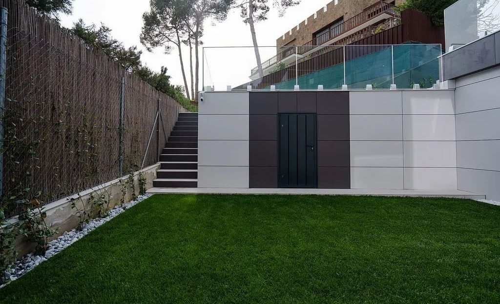 Участок виллы с газоном и подпорной стеной, приватная территория.