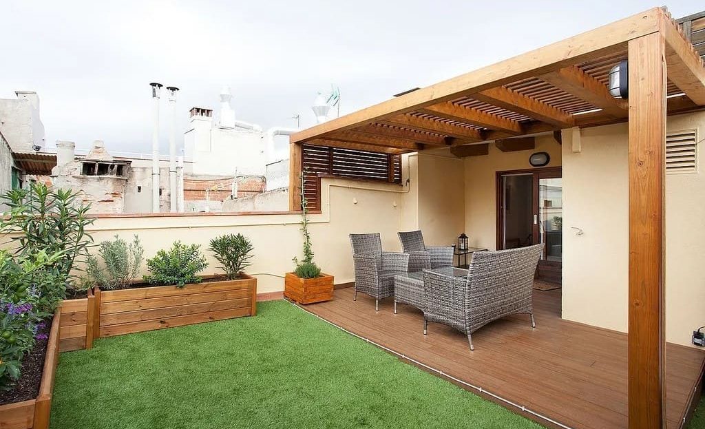 Просторная терраса с деревянным настилом и зелёным покрытием