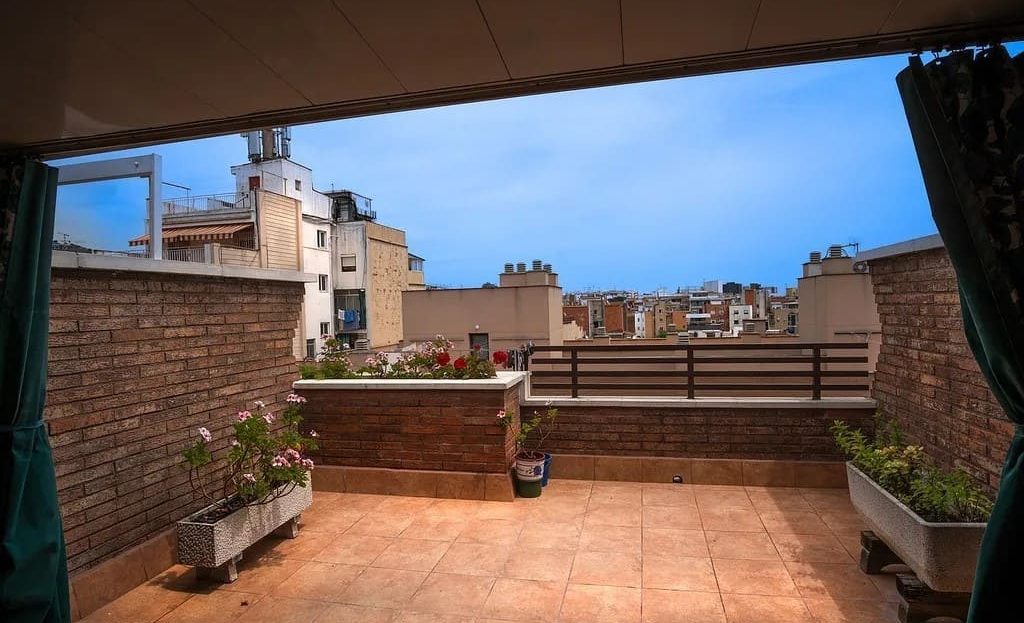 Просторная терраса пентхауса с зоной отдыха и видом на крыши домов