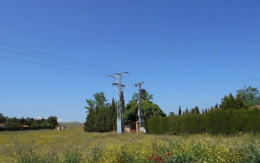 Участок земли в Реус — вид на поле с линиями электропередач и зелёными насаждениями