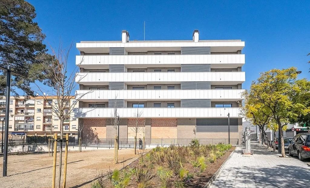 Современный фасад многоквартирного дома с зелёной зоной перед зданием