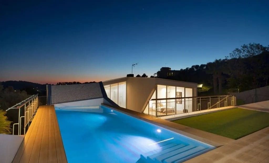 Вечерний вид на бассейн и террасу современного дома