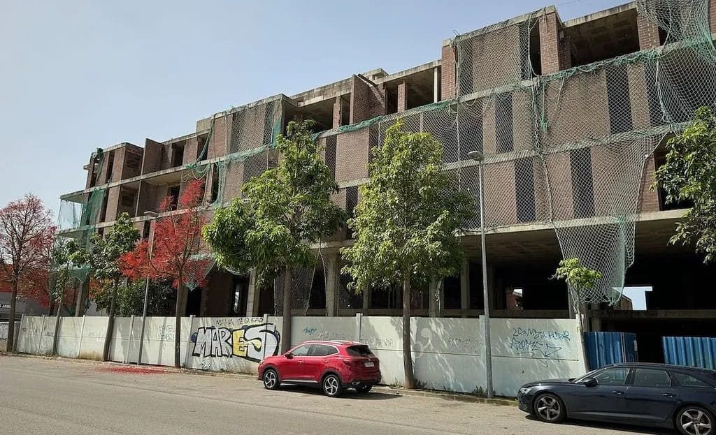 Вид здания под другим углом, видны балконы и частично смонтированный фасад.