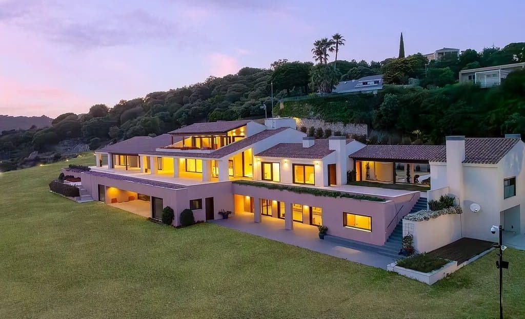 Вилла в вечернее время с освещёнными окнами и панорамным видом.