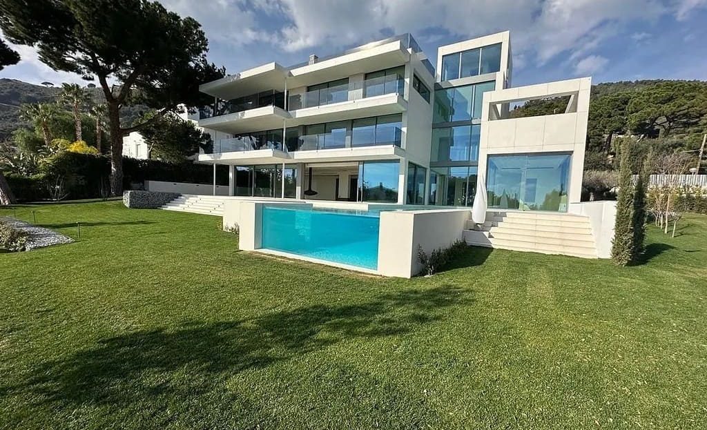 Вид на дом с газоном и бассейном на участке.