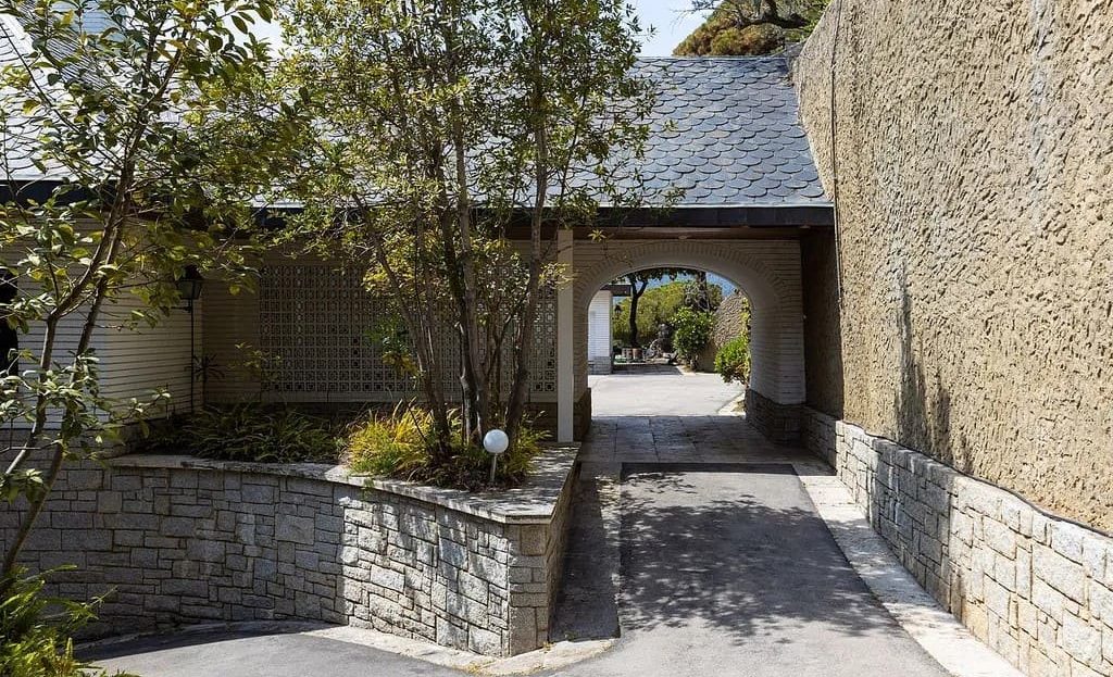 Въезд на территорию поместья с каменными стенами и аркой.