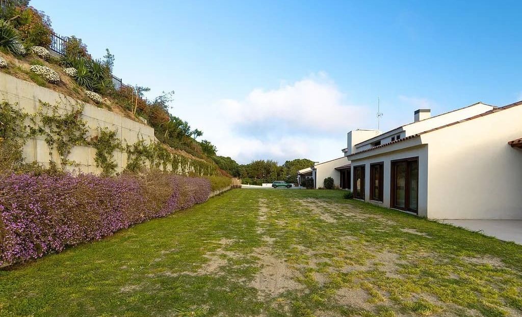 Участок с газоном и подъездной зоной рядом с домом.