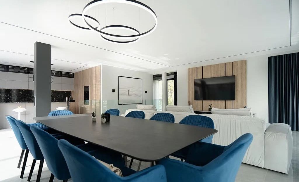 Столовая зона с большим обеденным столом и современным освещением.